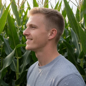 Tyler, a 26-year-old Ohio man in a gray t-shirt standing in a tall green cornfield